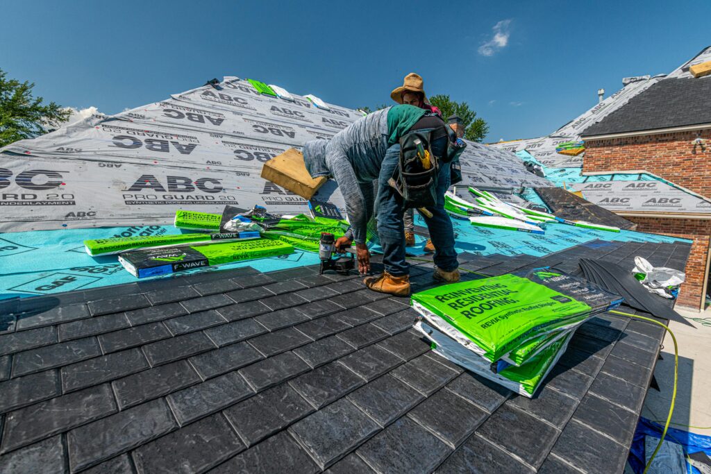 roofer installing shingles on a residential roof while wearing safety harness and helmet – workers’ compensation coverage for roofing contractors